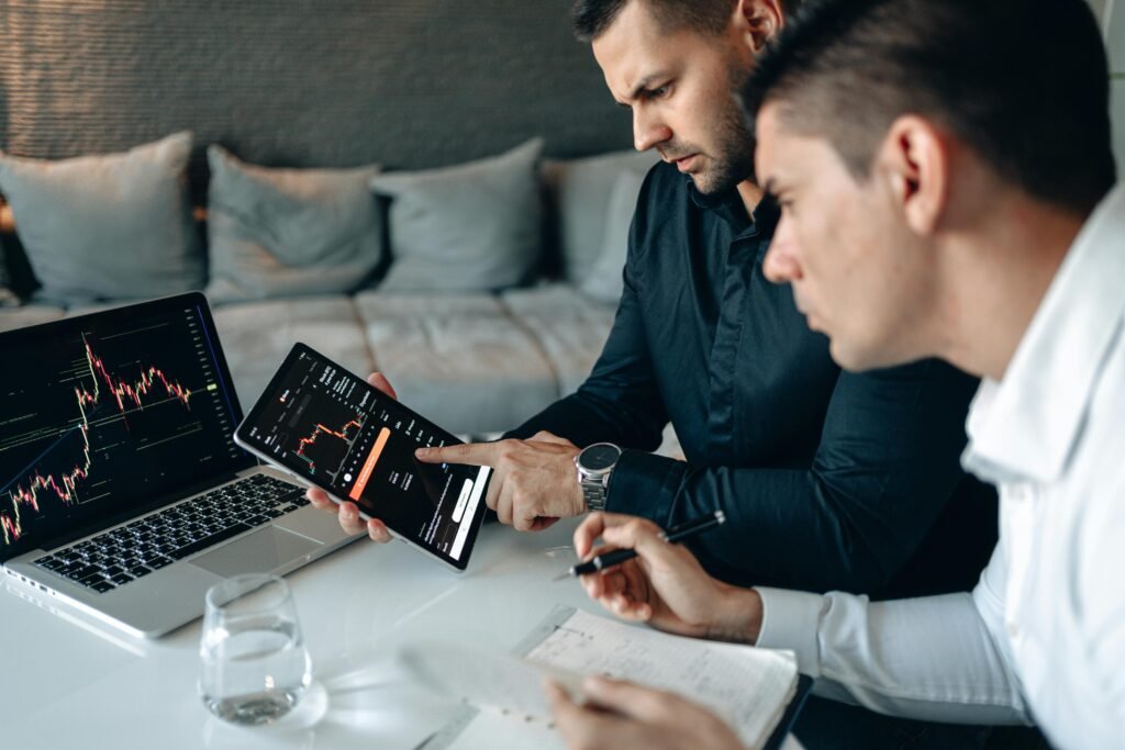 pexels-photo-4960420-4960420 Two business professionals using a laptop and tablet to analyze online trading data indoors.
